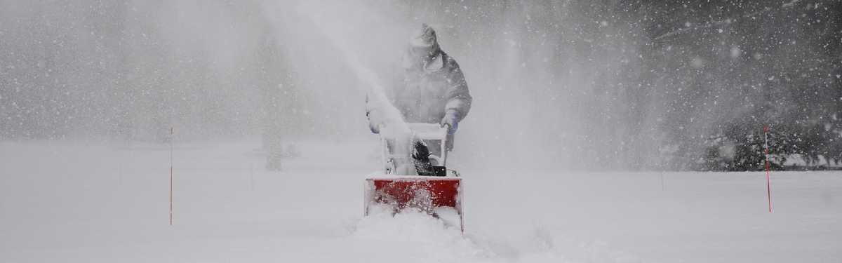 A man using a snowblower in a winter storm