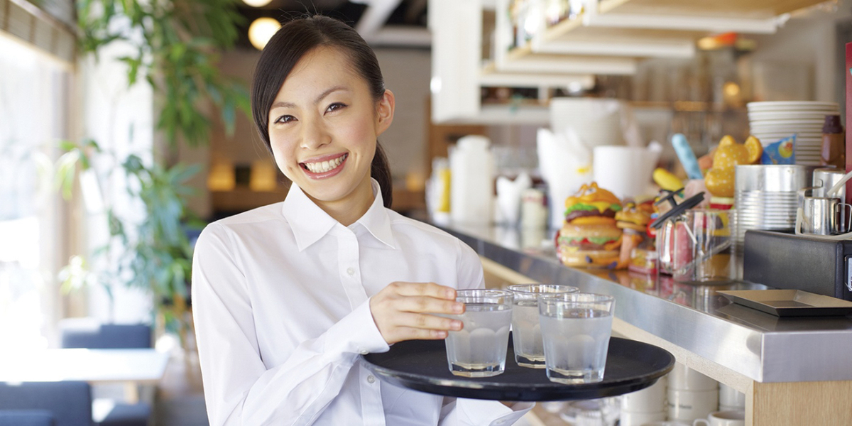 Smiling waitress holding a tray of glasses