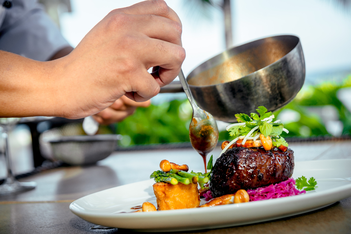 Chef pouring sauce over beef