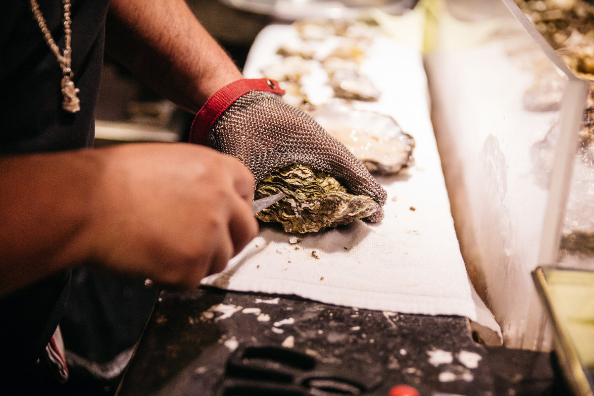 Man shucking oyster with glove on Man shucking oyster with glove on