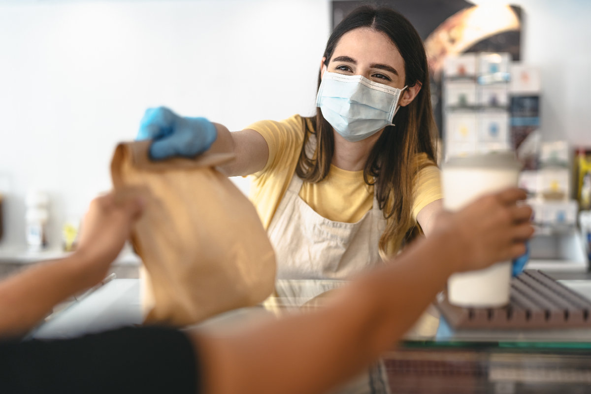 Server handing a customer take out while wearing a mask