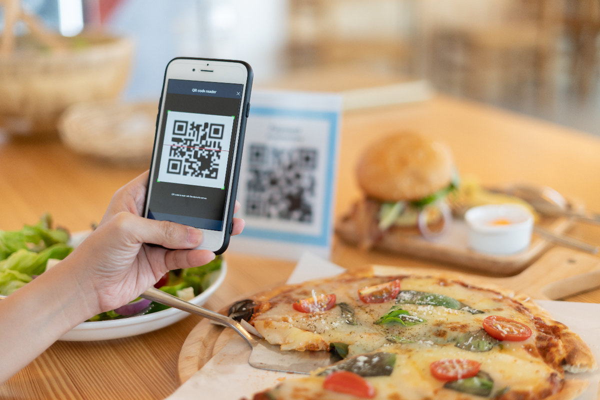 Person scanning QR Code on table with food on it